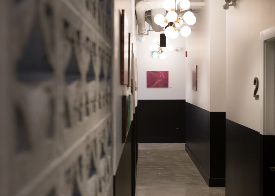 Hollyburn Eye Clinic — exam corridor with two-tone painted wainscoting, original artwork and globe pendants