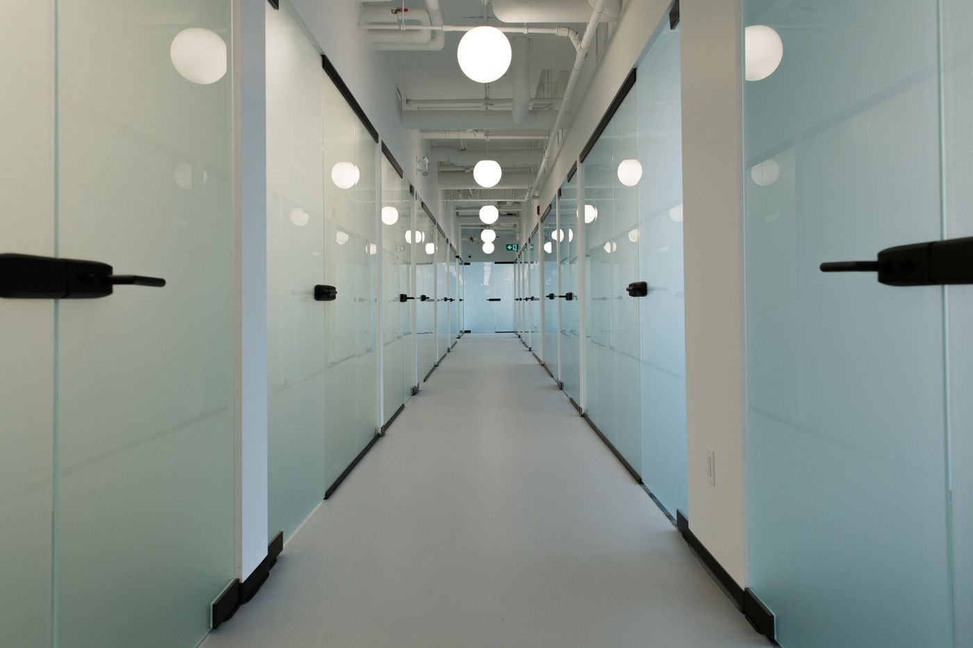 West Quay — glass office corridor with globe pendants receding to historic photomural